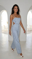 Woman wearing a light blue denim jumpsuit in a bright, white interior setting.