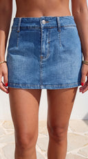 Person wearing a blue denim skirt with a neutral background