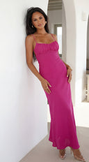 Woman wearing a pink dress standing against a white wall.