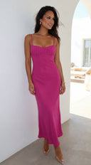 Woman wearing a pink dress standing in a bright room with white walls and a window.