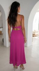 Woman in a pink dress standing in a sunlit room with white arches.