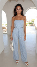 Woman wearing a light blue denim jumpsuit in an outdoor setting.