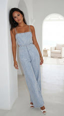 Woman wearing a light blue denim jumpsuit in a modern, minimalistic room.
