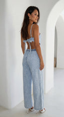 Woman wearing a light blue denim jumpsuit with a white background